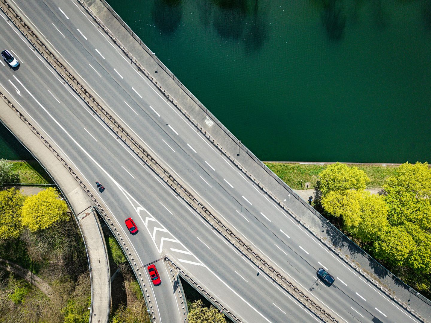 Aerial view of a road bridge and connecting ramp beside green water.